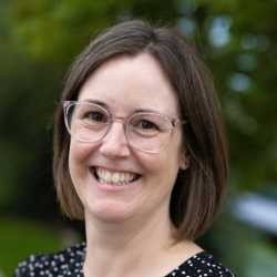 White woman with glasses and shoulder length brown hair